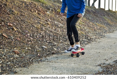 Young woman skating along a cement path in the late afternoon sun