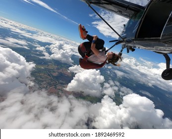 Young Woman Skydiver Jumping From The Plane Performing Front Loopings. Fearless And Confident. 