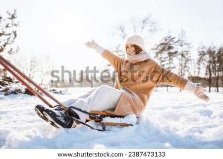 A young woman with a sled rides in a snowy park. Beautiful woman having fun outdoors on winter holidays. Fun, travel concept.