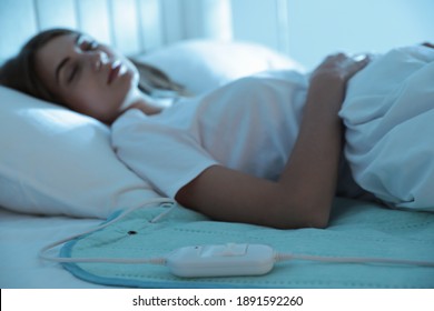 Young Woman Sleeping In Bed With Electric Heating Pad, Focus On Cable