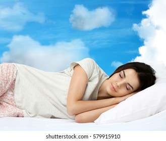 Young woman sleeping in bed and sky background