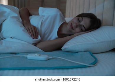 Young Woman Sleeping On Electric Heating Pad In Bed At Night