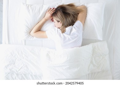 Young Woman Sleeping On Her Stomach In White Bed Top View