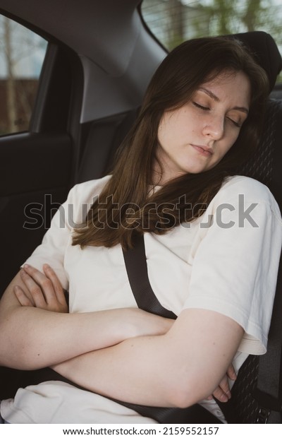 Young woman sleeps in the back seat of a\
car. Taxi passenger, travelling by\
automobile