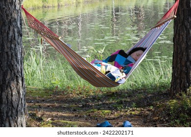 A young woman sleeps in a hammock in the forest. Family vacation concept - Powered by Shutterstock