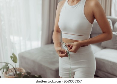 Young woman with slim body measuring her waist. Weight loss, healthy lifestyle concept.