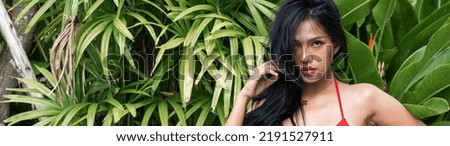 Young woman slim tanned body in bikini on Palm leavers ,positive redhead woman with clean skin and natural beauty standing behind tropical leaf, summer vacation skincare concept. bikini in nature

