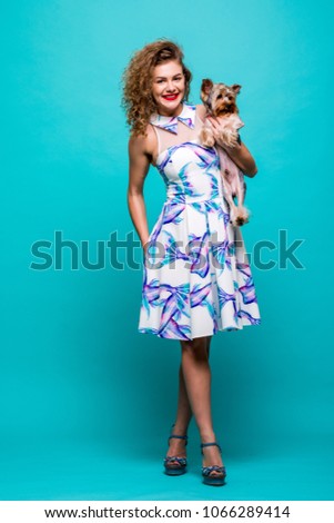 Young woman with small dog Yorkshire terrier stands in full height isolated on green