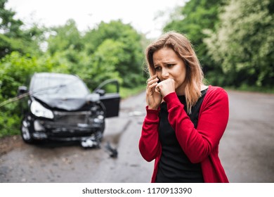 A Young Woman With Smartphone By The Damaged Car After A Car Accident, Making A Phone Call.