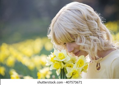 A Young Woman Smelling A Bunch Of Daffodils