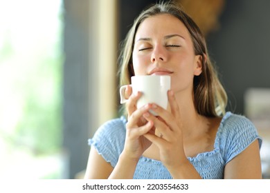 Young Woman Smelling Coffee Aroma From Cup In A Restaurant