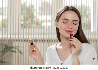 Young woman smelling essential oil indoors, space for text - Shutterstock ID 2238176151
