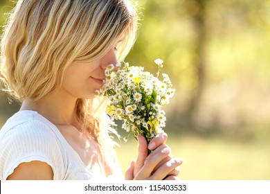 Young Woman Smelling Flowers In Nature