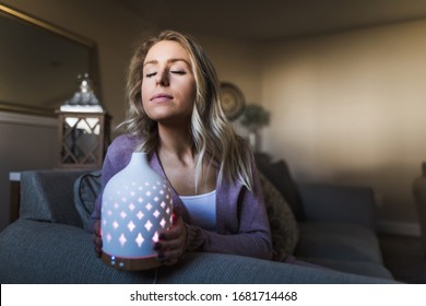 Young woman smelling her essential oil diffuser