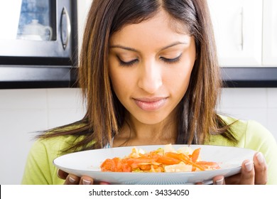 Young Woman Smelling Warm Food In Kitchen