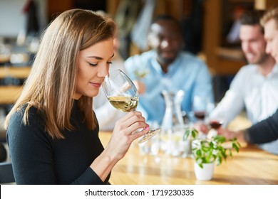 Young Woman Smells A Glass Of White Wine During A Wine Tasting Or Tasting