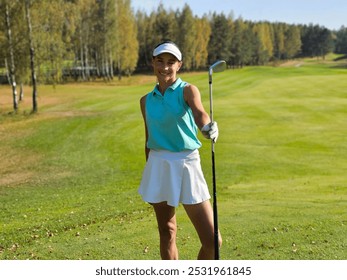 A young woman smiles confidently while holding a golf club on a sunny day at a scenic golf course surrounded by trees - Powered by Shutterstock