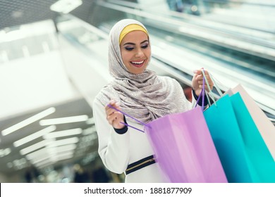 Young woman smiles while she looks inside the package. Beautiful woman bought new clothes at the mall.  - Powered by Shutterstock