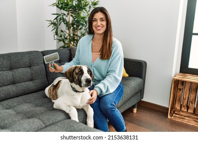 Young Woman Smiling Confident Using Pet Hair Remover Brush At Home