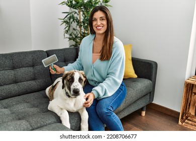 Young Woman Smiling Confident Using Pet Hair Remover Brush At Home