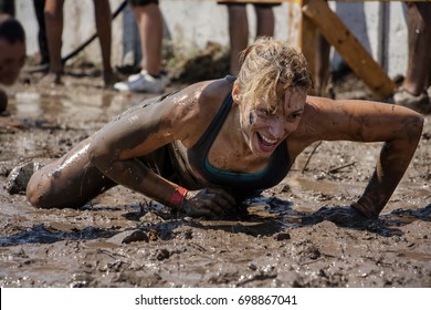 Young woman smiling and crawling under barbed wire; concept of winning, endurance, strength and fun - Powered by Shutterstock