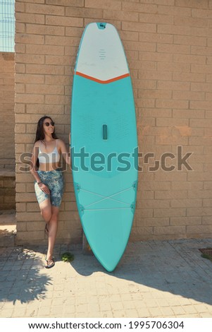 Surfer woman with bikini and wetsuit holding surfboard