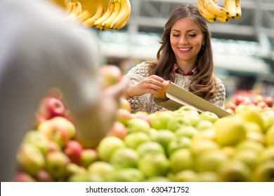 Young Woman Smiling And Holding Fruit At Market
