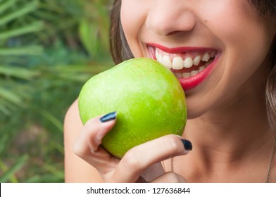 Young woman smiling holding a green apple