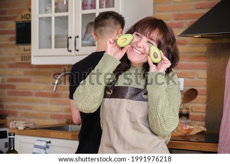 Young woman smiling and playing with an avocado. Cooking time.