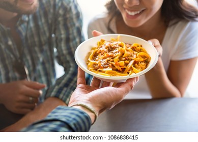 Young woman smiling with pleasure while getting pasta that just ordered at counter of food truck