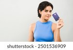 Young woman smiling while holding a credit card in a studio setting, showcasing the convenience of modern banking