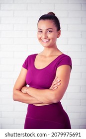 Young Woman Smiling Yoga Instructor Portrait And  Pilates Teacher At Gym. White Wall Background And Purple Clothes