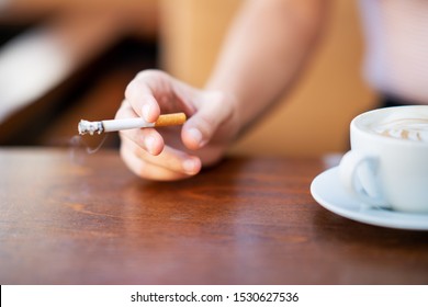 Young woman smoking and holding cup of coffee in a cafe. - Powered by Shutterstock