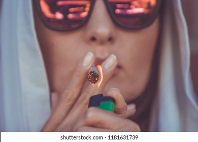Young woman smoking marijuana joint - medical marijuana use and legalization of cannabis concepts - closeup of lighting a weed cigarette in Amsterdam (Holland - Netherlands)