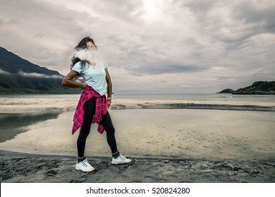 Young woman is smoking the vape on the beach of Norway