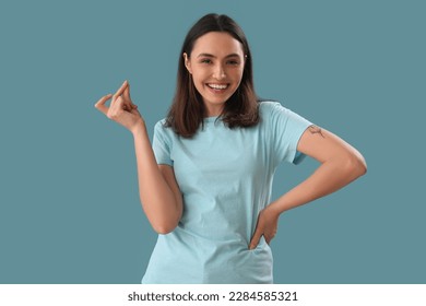Young woman snapping fingers on blue background