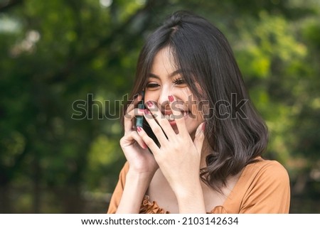 A young woman snickers while keep in touch with her friend over the phone.