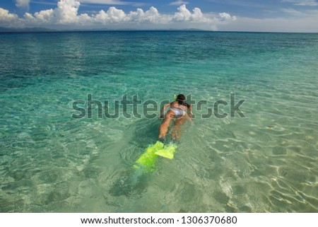 Young woman snorkeling in clear shallow water near tropical island