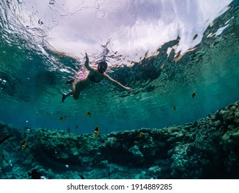 Young woman snorkeling at coral reef in tropical sea