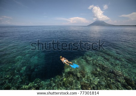 Young woman snorkeling over coral reef in transparent tropical sea. Bunaken island. Indonesia