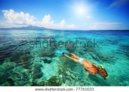 Young woman snorkeling over coral reef in transparent tropical sea. Bunaken island. Indonesia
