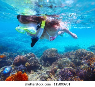 Young woman snorkeling over vivid coral reef in tropical sea