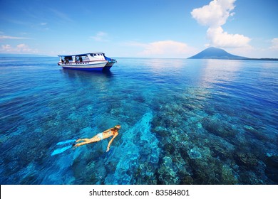 Young woman snorkeling in transparent shallow sea near boat
