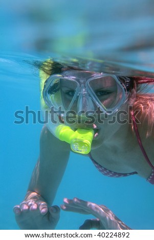 Young woman snorkeling in tropical warm blue water.