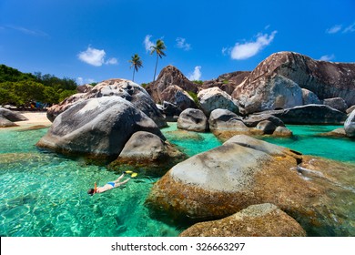 Young Woman Snorkeling In Turquoise Tropical Water Among Huge Granite Boulders At The Baths Beach Area Major Tourist Attraction On Virgin Gorda, British Virgin Islands, Caribbean