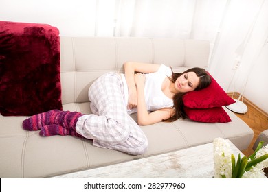 Young woman in the sofa with period pain