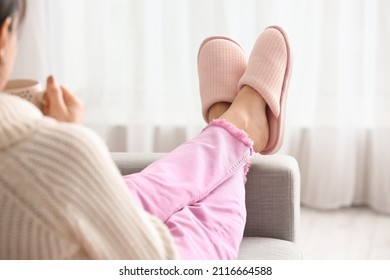 Mujer joven con zapatillas cómodas y suaves tomando té en casa