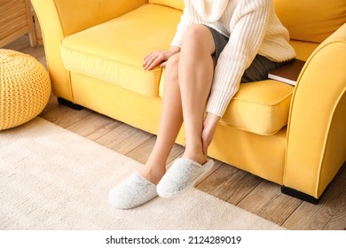Mujer joven con zapatillas cómodas y mullidas sentada en el sofá