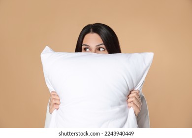 Young woman with soft pillow on beige background