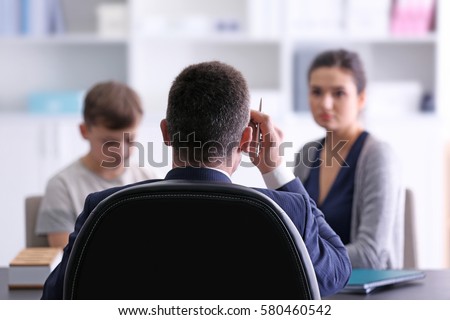 Young woman with son during teacher-parent meeting at school